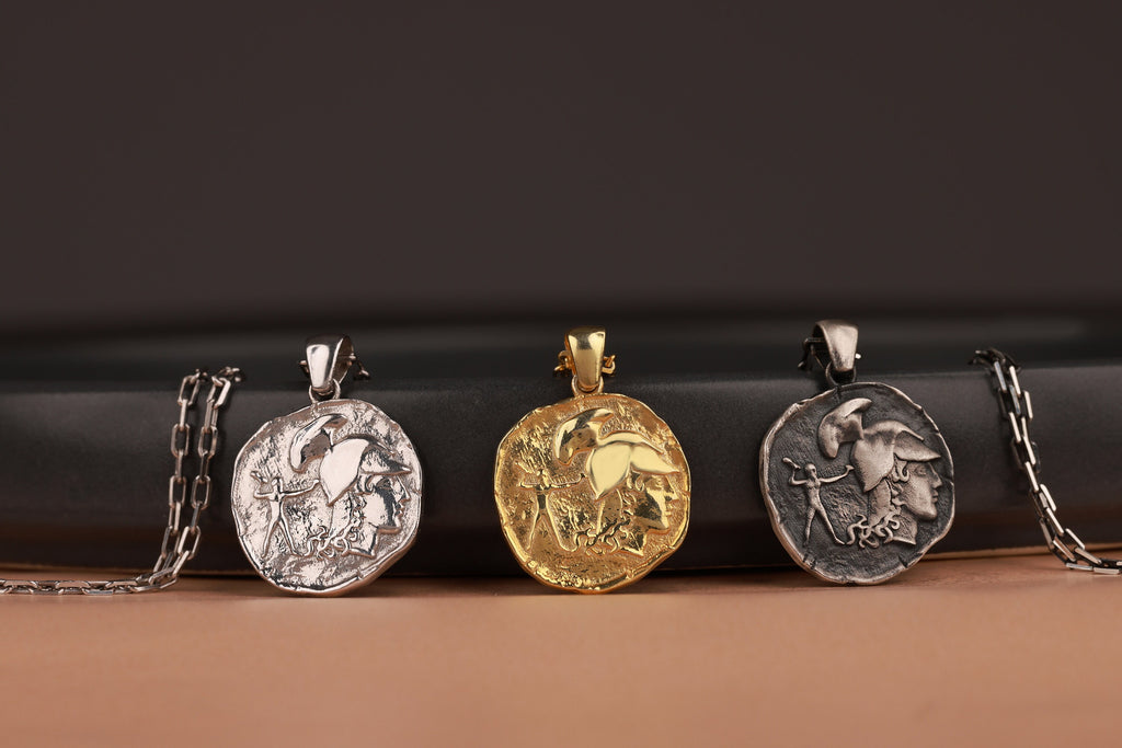 Four coin pendants on chains against a dark background