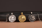Four coin pendants on chains against a dark background