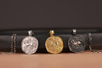 Three coin pendants on a black leather strap against a dark background