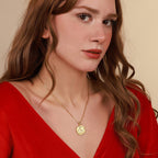 Woman wearing a gold necklace with a coin pendant against a beige background