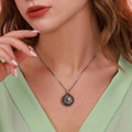 Close-up of a necklace with a pendant worn by a person in a light green top.