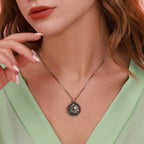 Close-up of a necklace with a pendant worn by a person in a light green top.