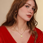 Woman wearing a gold jesus necklace with a pendant against a beige background