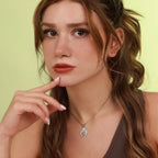 Woman wearing a necklace with a polished sacred heart pendant against a light green background