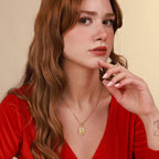 Woman wearing a gold sadred heart necklace with a beige background