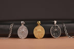 Three Our Lady of Charity pendants on chains against a dark background