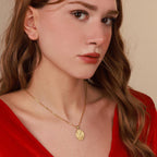 Woman wearing a gold virgin mary necklace with a pendant against a neutral background