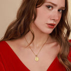 Woman wearing a gold Risen Savior necklace with a pendant against a beige background