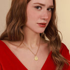 Woman wearing a gold religious necklace with a pendant against a beige background