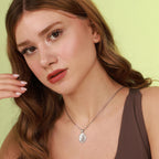 Woman wearing a necklace with a jesus pendant against a light green background