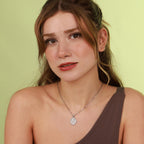 Woman wearing a necklace with a christian pendant against a light green background
