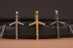 Three grapevine orthodox cross-shaped pendants in silver, gold, and another metal on a black background