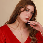 Woman wearing a gold necklace with a grapevine cross pendant against a beige background