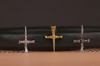 Three gold, polished, oxidized nail crosses on a black and brown gradient background