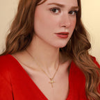 Woman wearing a gold vermeil necklace with a nail cross pendant against a beige background