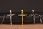 Three crucifix pendants in silver, gold, and bronze on a black background