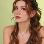 Woman with long brown hair wearing a polished sterling silver necklace with an archangel cross pendant against a light green background