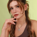 Woman wearing a polished nativity necklace with a pendant against a light green background
