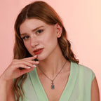 Woman wearing a green top and a silver necklace with a pink background