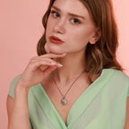 Woman wearing a green dress and necklace against a pink background