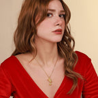 Woman wearing a red top and gold nefertiti necklace against a beige background