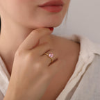 Close-up of a hand wearing a pink gemstone ring with a neutral background
