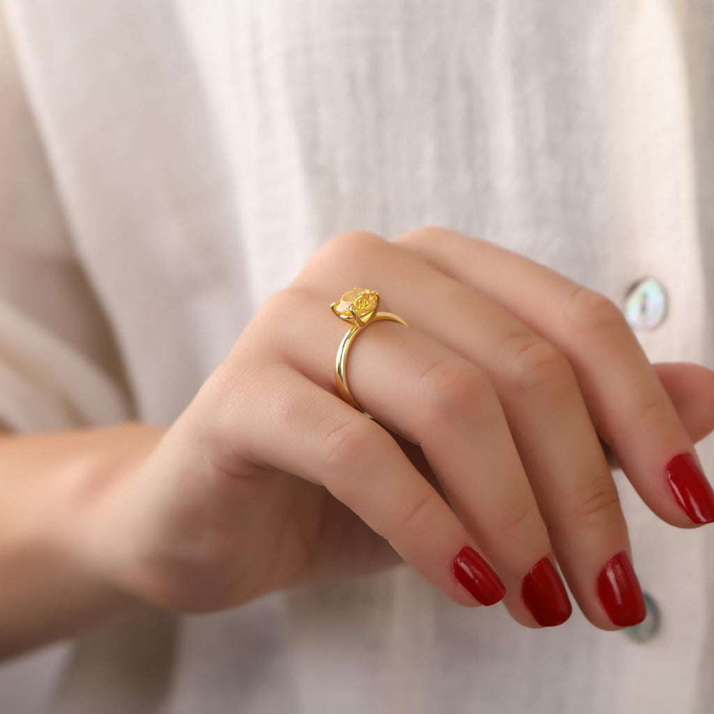Hand wearing a gold ring with a red nail polish against a white background