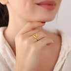 Close-up of a person wearing a yellow gemstone ring on a plain background