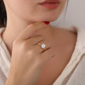 Close-up of a person wearing a gold ring with a diamond on a plain background