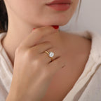 Close-up of a person wearing a gold ring with a diamond on a plain background