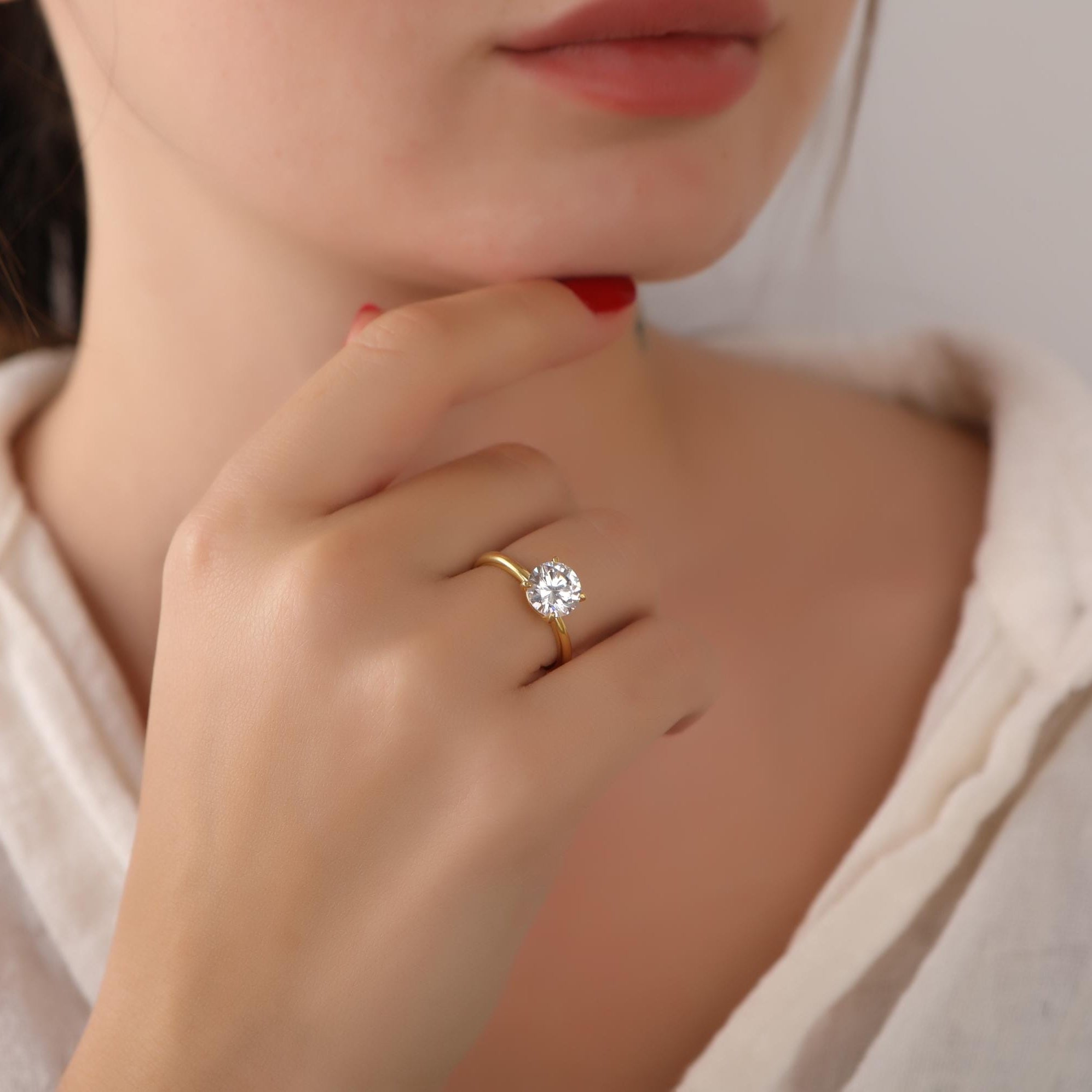 Close-up of a person wearing a gold ring with a diamond on a plain background