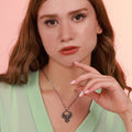 Woman wearing a phoenix necklace with a pink background