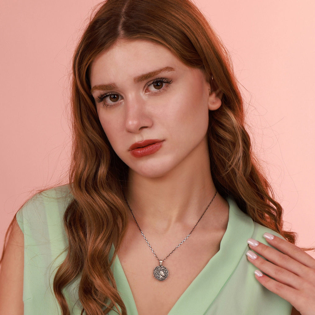Woman wearing a silver necklace against a pink background