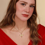 Woman wearing a gold necklace with a dragonfly pendant against a beige background
