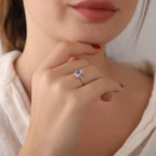 Close-up of a hand wearing a ring with a diamond, held near the chin.