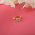 Gold ring with a pink gemstone on a red background with white flowers.