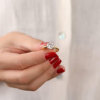 Hand holding a diamond ring with a plain background