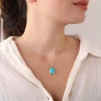 Necklace with a turquoise pendant worn by a person in a white shirt.