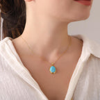 Necklace with a turquoise pendant on a mannequin wearing a white blouse.