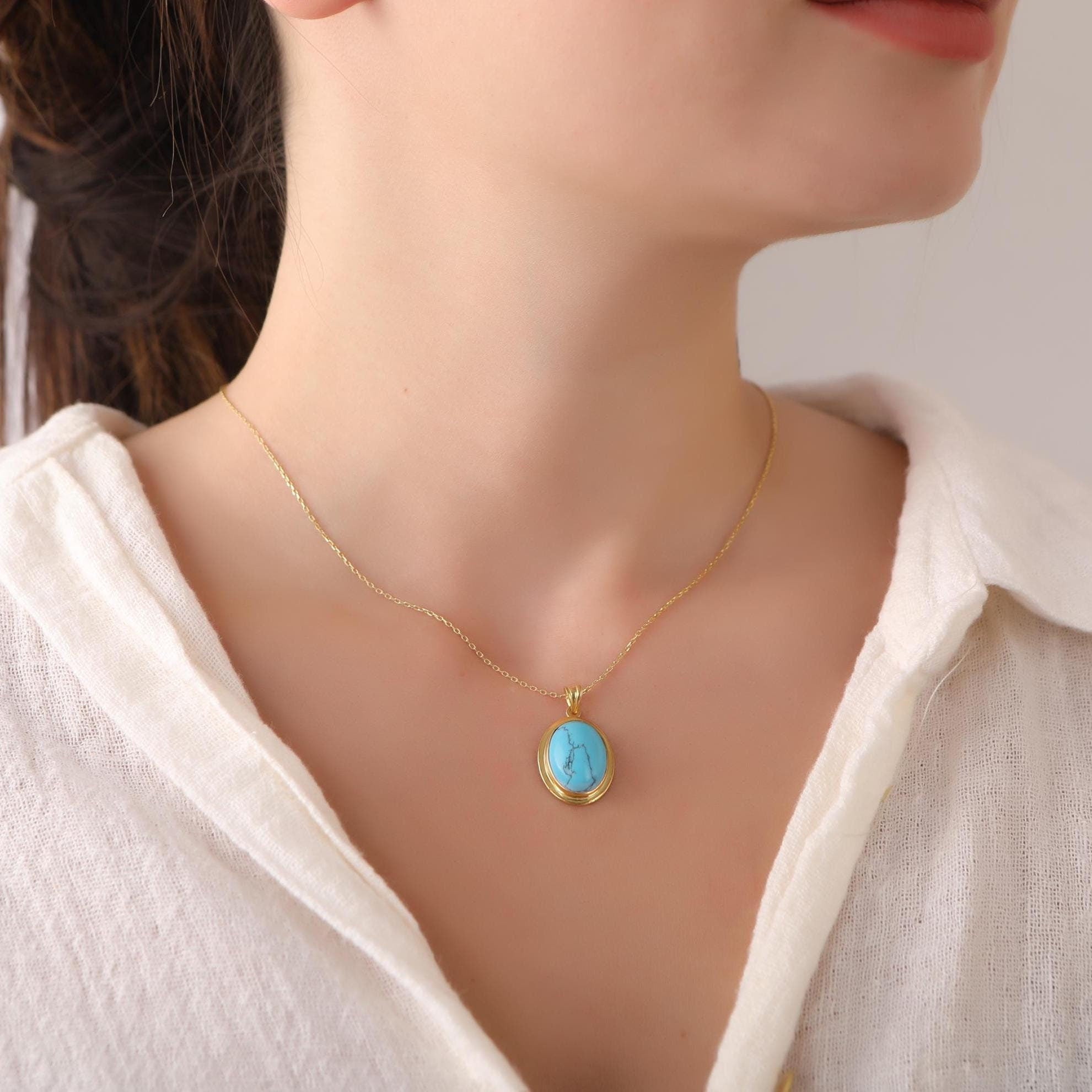 Necklace with a turquoise pendant on a mannequin wearing a white blouse.