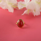 Gold ring with a red stone on a background with flowers