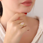 Close-up of a woman's hand wearing a gold rose quartz ring