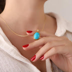 Woman wearing a gold necklace with a turquoise pendant, close-up of the necklace.