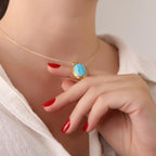 Close-up of a person wearing a gold necklace with a turquoise pendant, hand resting on shoulder.