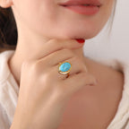 Close-up of a turquoise ring with a gold band worn by a person