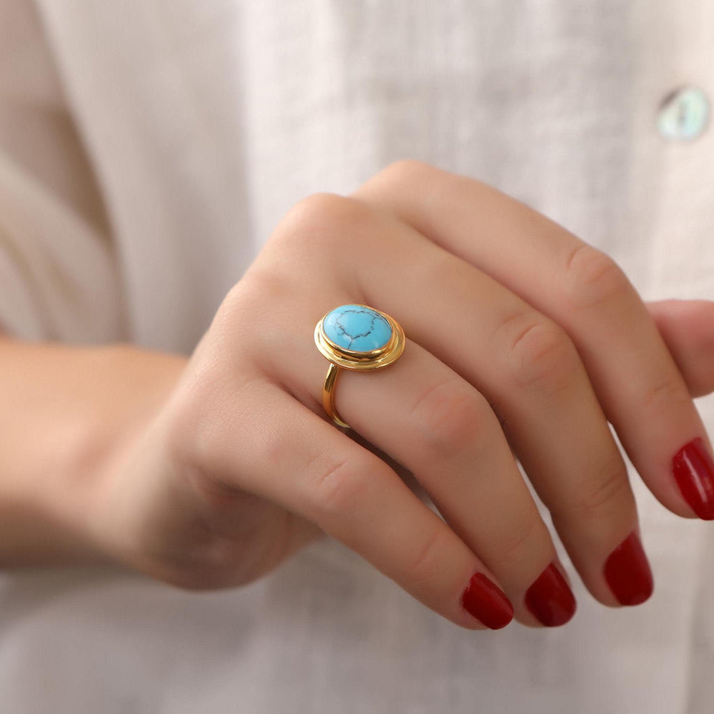 Gold ring with a turquoise stone wearing by with red nails hand