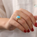Gold ring with a turquoise stone wearing by with red nails hand