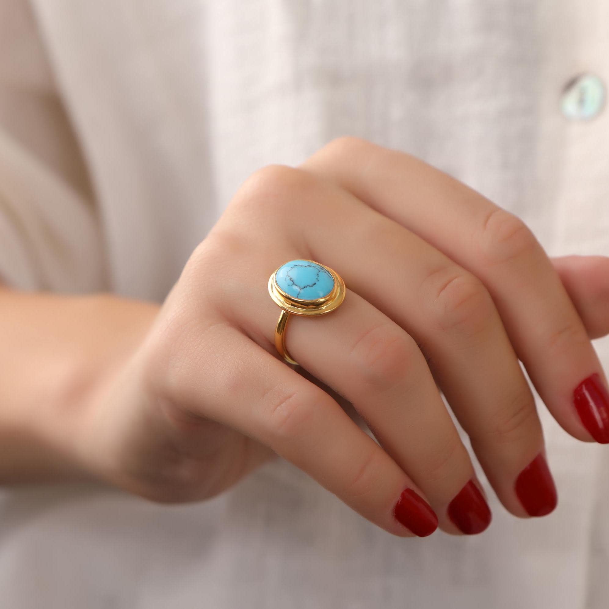 Gold ring with a turquoise stone wearing by with red nails hand