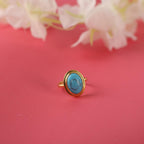 Gold ring with a blue gemstone on a pink background with flowers