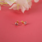 Gold stud earrings with round-cut pink tourmaline gemstones on a red background